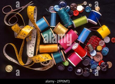 Close up still life assorted colourful objects for needlework & sewing cotton reels & fine threads buttons needle metric imperial tape measure UK Stock Photo