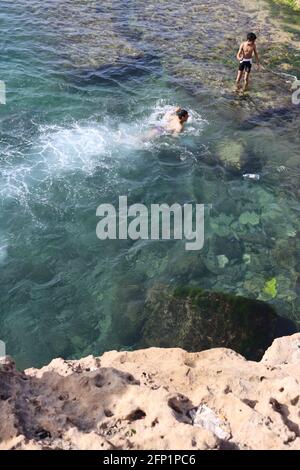 In Alexandria Egypt on the sea there are people, cliff, marine eagle, rocks, young men swimming on the sea with seascape, and beauty nature. Stock Photo