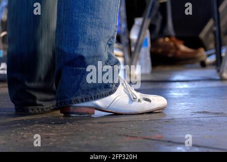 A male buck dancer wearing a white tap shoe awaits his performance during a folk festival featuring traditional dance of the Piedmont region. Stock Photo