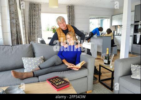 A retired couple spending time with their grandchildren on a holiday in Cornwall UK. The couple relax in a holiday apartment. Stock Photo