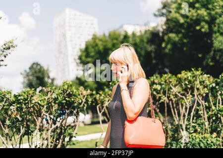 Beautiful business woman talking over the phone and walking in city street Stock Photo