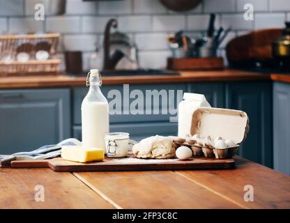 Assorted ingredients for pastry preparation placed on wooden chopping board on table in kitchen. Rustic style Stock Photo