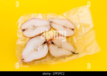 Pears cut in half in vacuum sealed for sous vide cooking, isolated on yellow background Stock Photo