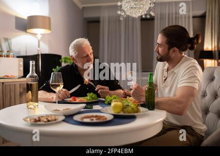 Grandfather and grandson talking during dinner Stock Photo