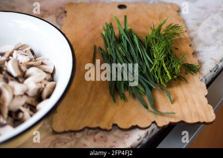 Plate of chopped mushrooms, green onions, dill on cutting board Stock Photo