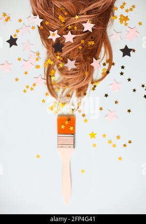 From above of soft silky hair on white background with brush aside all in scattered star shaped confetti Stock Photo