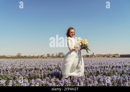 portrait of woman standing on hyacinth fields and holding tulips Stock Photo