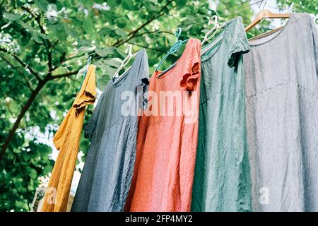 Colorful dresses hanging on hangers on the clothesline in the home garden Stock Photo