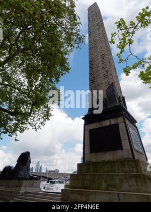 London, Greater London, England - May 18 2021: Cleopatras Needle an Eqyption Obelisk and a bronze Spinx statue near Embankment Gardens. Stock Photo