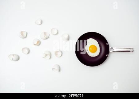 scrambled eggs with whole yolk on pan and broken shells Stock Photo