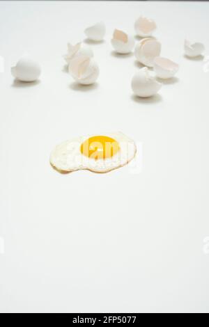 scrambled eggs with whole yolk and broken shells on white background Stock Photo