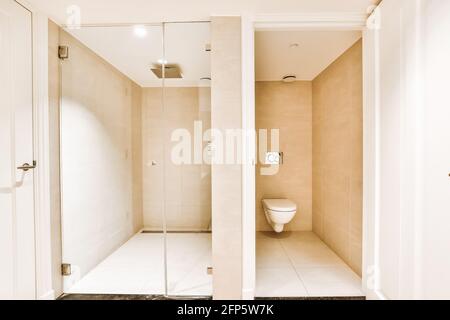 Separate toilet and modern spacious shower cabin with rain shower mounted on ceiling Stock Photo