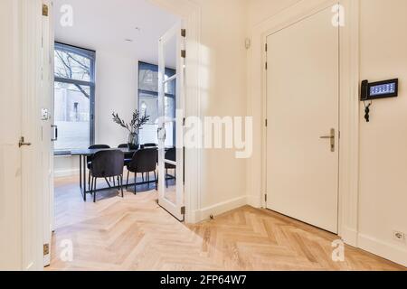 Hallway with security system screen on wall and wooden parquet flooring with opened doorway to living room