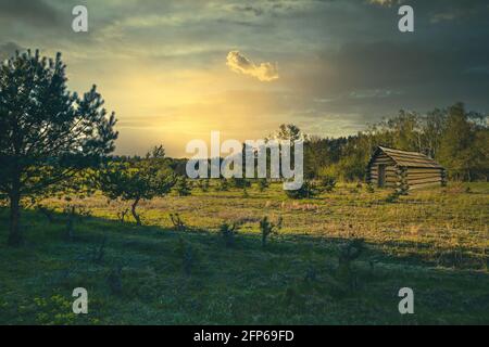 A lonely wooden hut on the bank of a small river covered in fog. Stock Photo