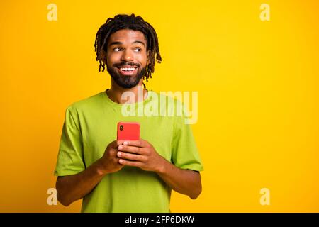 Photo of surprised dark skin guy hold smartphone look copyspace repost subscribe isolated over shine color background Stock Photo