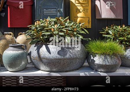 Selection of clay amphorae and pots of various shapes and colors on a shelf against the background of decorative mailboxes hanging on a shabby wall Stock Photo
