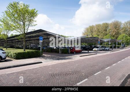 Solar energy panels installed on the canopy of a car parking area in the center of the dutch city Dronten. Sustainable energy and shade Stock Photo