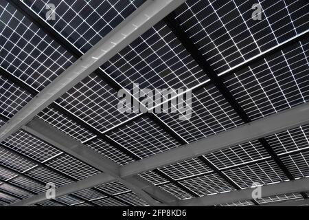 Solar energy panels installed on steel beams to cover a car park, seen from below. Sustainable energy and shade at the same time Stock Photo