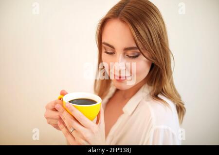 Adult female in robe closing eyes while having cup of aromatic freshly brewed black coffee Stock Photo