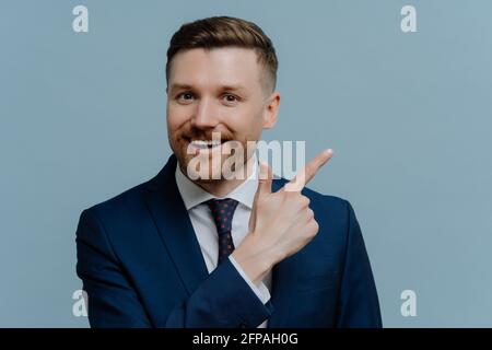 Cheerful businessman pointing with his finger at copy space Stock Photo