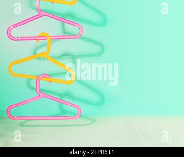 Sale composition with colored plastic hangers hung on top of each other on a mint background with shadows and copy space. The concept of summer sale Stock Photo