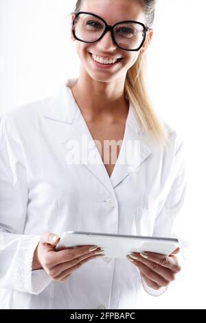 Studio portrait of a happy heatlcare provider as nurse or doctor looking at camera while holding a PC Tablet for checking medical information against Stock Photo