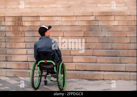 young disabled man in wheelchair in front of stairs Stock Photo