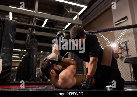 confident MMA boxers fighters fight in fights without rules in ring octagons. Mixed martial artists during fight. sport and boxing concept Stock Photo