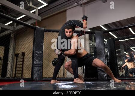 Athlete MMA boxers fighters fight in fights without rules in ring octagons. Mixed martial artists during fight. sport and boxing concept Stock Photo