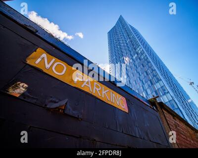 old no parking sign below modern tall sky scrapper building Stock Photo