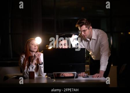 Group of young confident business colleagues in team discussing startup project at night. tired sleepy Caucasian Business People with pc computer work Stock Photo