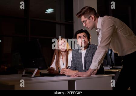 Caucasian Business people team working late night using computer. Overtime hours concept. Brainstorming time, miss the deadline. side view on young bu Stock Photo