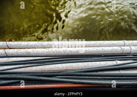 electrical cables and pipes over dirty water Stock Photo