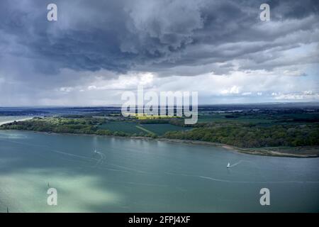 Dark cumulus storm clouds over the West Sussex countryside and estuary near Chichester Marina with sailing boats in the water. Aerial photo. Stock Photo