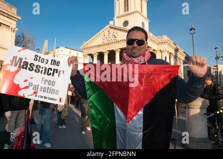 TRAFALGAR SQUARE, LONDON - JANUARY 9, 2009: Freedom for Palestine demo, a man in dark glasses standing, holding a Palestinian flag in front of him Stock Photo