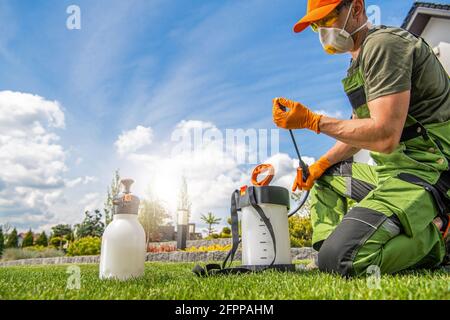 Caucasian Worker in His 40s Preparing Pest Control Spraying Equipment. Spring Garden Maintenance Theme. Stock Photo