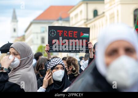 Demonstranitn hält Schild mit Aufschrift: ' Free Palestine/Stoppt alle militärische Zusammenarbeit und Handel mit Apartheid Israel & ähnlichen kriminellen Regimen der Unterdrückung weltweit! ' Ca. 600 Menschen versammelten sich am 20.5.2021 in München, um ihre Solidarität mit den Menschen in Gaza, Ost Jerusalem, den besetzten Gebieten und dem Westjordanland zu zeigen. - Around 600 people gathered on May 20, 2021 in Munich, Germany to show their support for the people in Gaza, East Jerusalem, the occupied territories and the Westbank. (Photo by Alexander Pohl/Sipa USA) Stock Photo