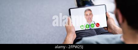Man Having Video Chat With Doctor On Laptop At Home Stock Photo