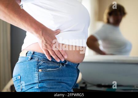 Older Overweight Woman With Excess Body Fat Looking In Mirror Stock Photo