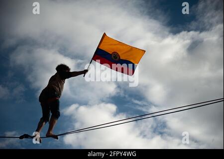 An equilibrist waves a Colombian flag as  demonstrator doing as Colombia enters its 4th week of anti-government protests against police brutality that