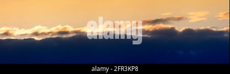 Evening sunset panorama with dark blue clouds and orange light clouds Stock Photo