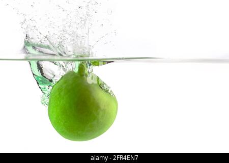 one green apple falling into water on a white background with splashes, drops and bubbles Stock Photo