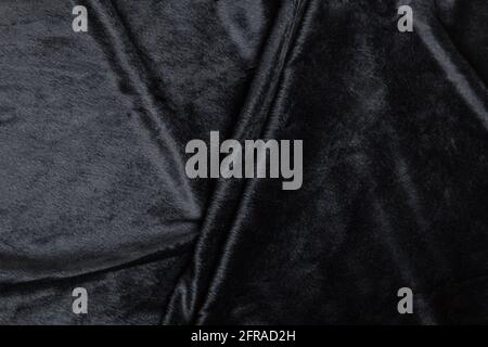 Colored black textile satin fabric folded in folds and waves with highlights and texture shimmers in the light Stock Photo