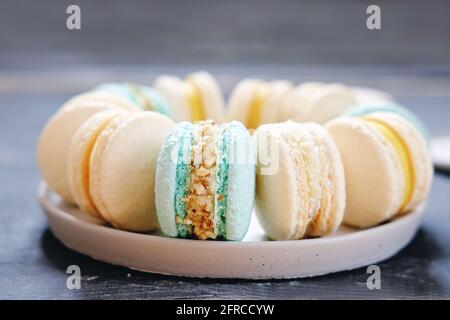 close up view of pastel colored macaroons on a plate. lemon nut filling ganache for french traditional dessert cookies. almond flour pastry. hand made Stock Photo