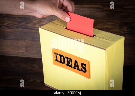 Ideas. Business concept. Yellow ballot box on a wooden background. Stock Photo