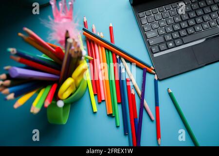 Colored pencils in a green circle on the blue table. Many different colored pencils. Stationery.  Stock Photo