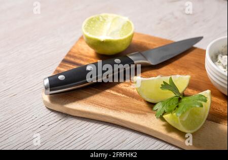 Sliced lime and black knife on wooden cutting board Stock Photo