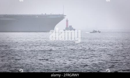 A US Navy Aircraft Carrier is escorted out of Yokosuka harbor in to  the fog of Tokyo Bay in Japan. Stock Photo