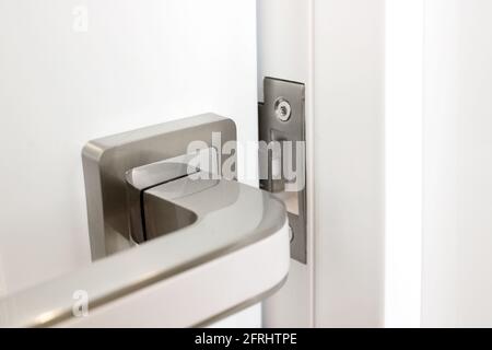 Modern metal handle on white door close-up interior detail Stock Photo