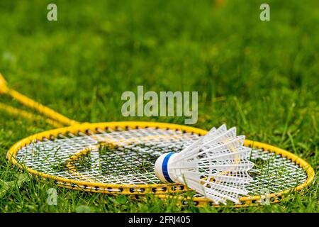 white shuttlecock on yellow badminton rackets in the green meadow Stock Photo